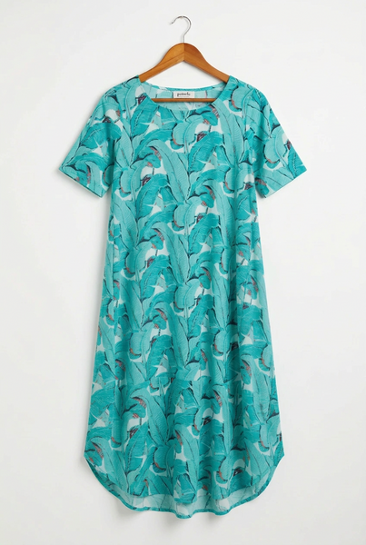 A short-sleeve A-line dress with a vibrant teal and turquoise tropical leaf print, hanging on a wooden hanger against a plain white wall.