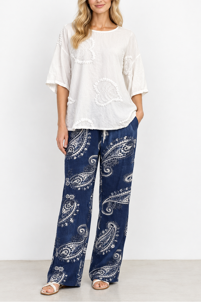 White lace top and blue paisley pants on a mannequin against a gray background