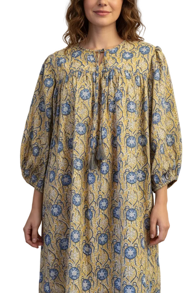 Woman wearing a yellow dress with blue floral pattern on a white background