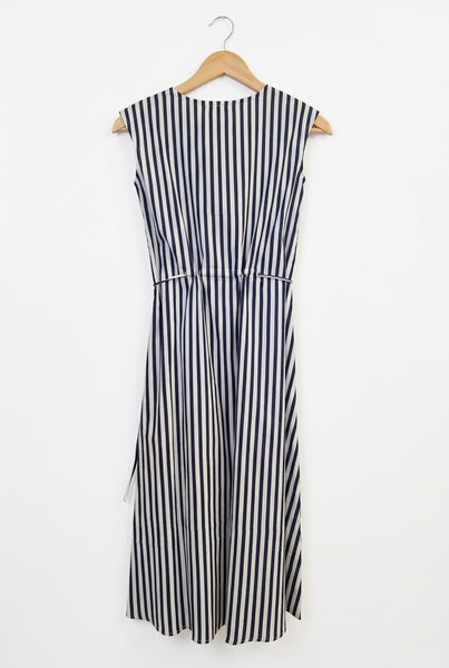 A sleeveless dress with vertical navy blue and white stripes, laid flat on a white fabric background.
