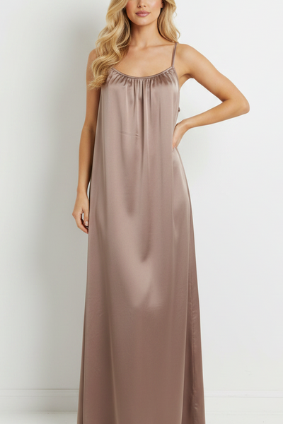 Woman wearing a long, light brown dress against a white background