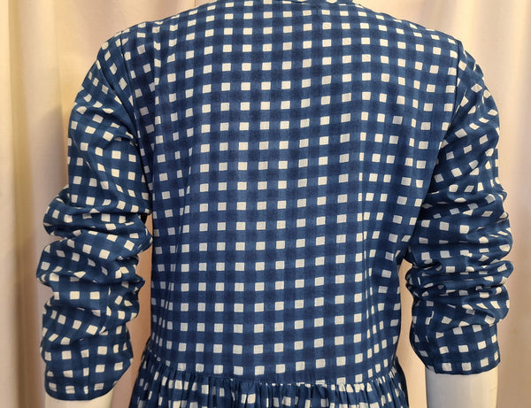Blue and white checkered dress on a mannequin against a beige background