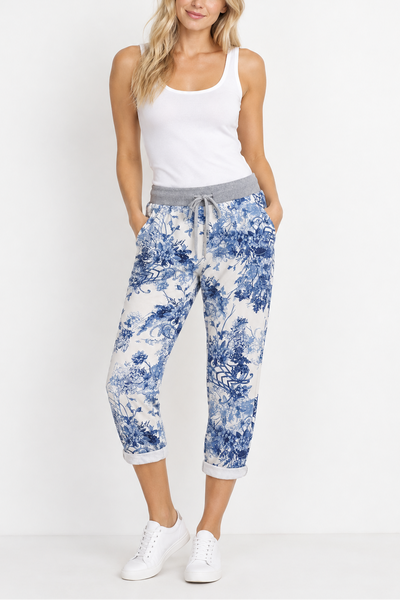 Blue and white floral pants on a hanger against a neutral background