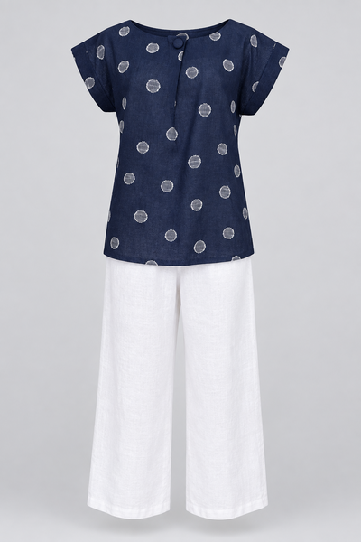 Navy linen top with large white spots paired with white trousers, displayed on a mannequin.