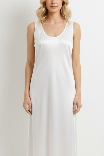 A woman modeling a sleeveless white maxi dress with a scoop neckline against a plain light gray studio background.